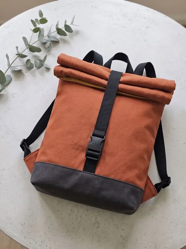 The ROLL Pack: tall rust roll-top backpack with a dark base band